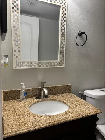 a bathroom with a granite countertop sink and a mirror