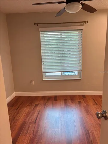 a view of an empty room with wooden floor and a window