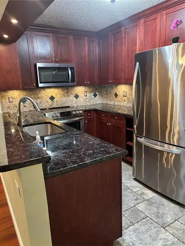 a kitchen with granite countertop stainless steel appliances and wooden cabinets
