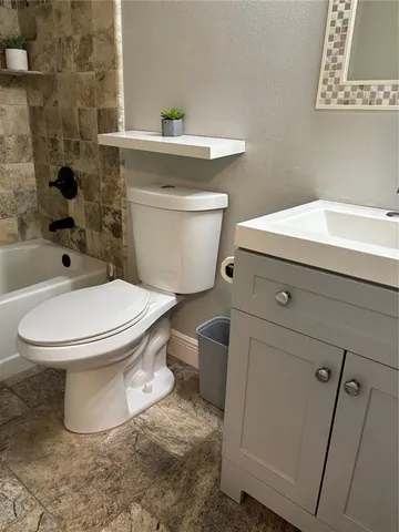 a white toilet sitting next to a bathroom sink and a mirror