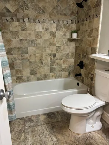 a white toilet sitting next to a bath tub and a shower