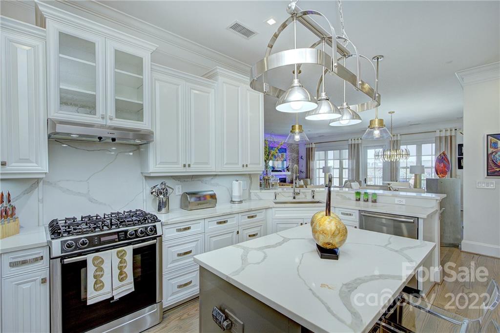 2823 Providence Road, Unit 254 Charlotte, NC 28211 - Photo 8 of 44 a kitchen with a stove a sink dishwasher a dining table and chairs with wooden floor