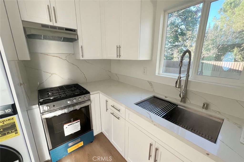 1133 Geraldine Avenue East, Unit B Lancaster, CA 93535 - Photo 9 of 27 a kitchen with a stove and white cabinets