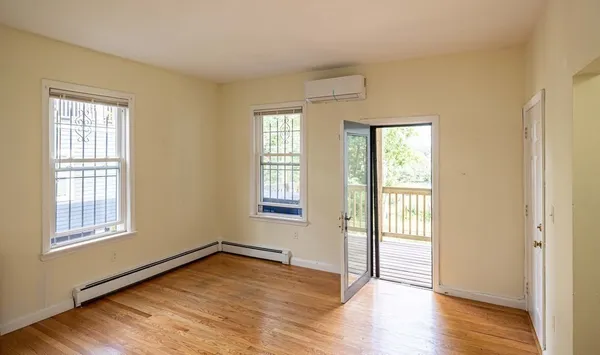 a view of an empty room with wooden floor and a window