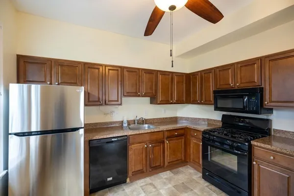 a kitchen with stainless steel appliances granite countertop a refrigerator a stove a sink and a microwave