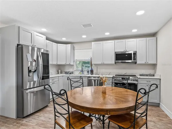 a kitchen with stainless steel appliances granite countertop a refrigerator a stove a sink a dining table and chairs