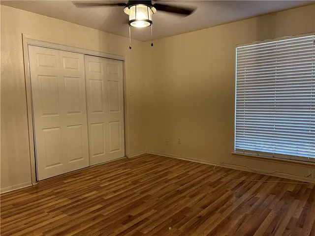 an empty room with wooden floor cabinet and windows