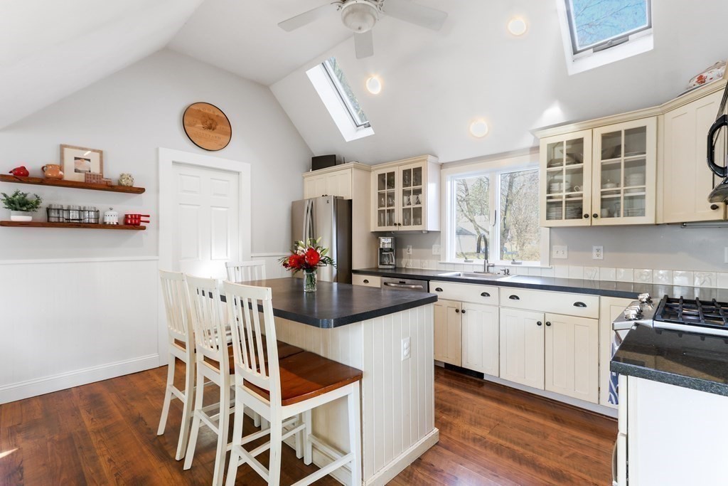 79 Kendall Lane Natick, MA 01760 - Photo 8 of 32 a kitchen with stainless steel appliances granite countertop a sink a stove a dining table and chairs with wooden floor