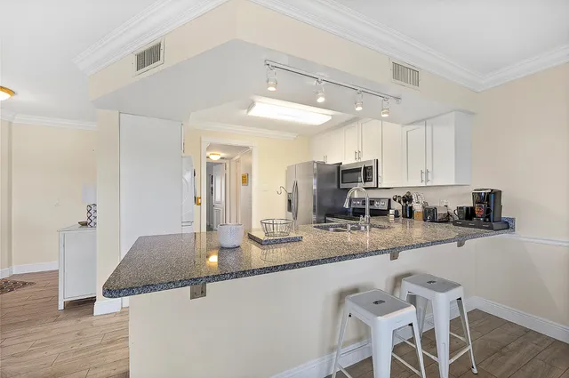 a kitchen with stainless steel appliances granite countertop a sink a stove a refrigerator and island with wooden floor