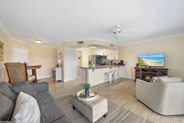 a living room with furniture kitchen view and a chandelier