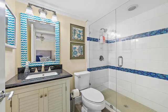 a bathroom with a granite countertop sink a toilet a mirror and shower