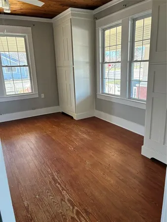 an empty room with wooden floor and windows with curtains view