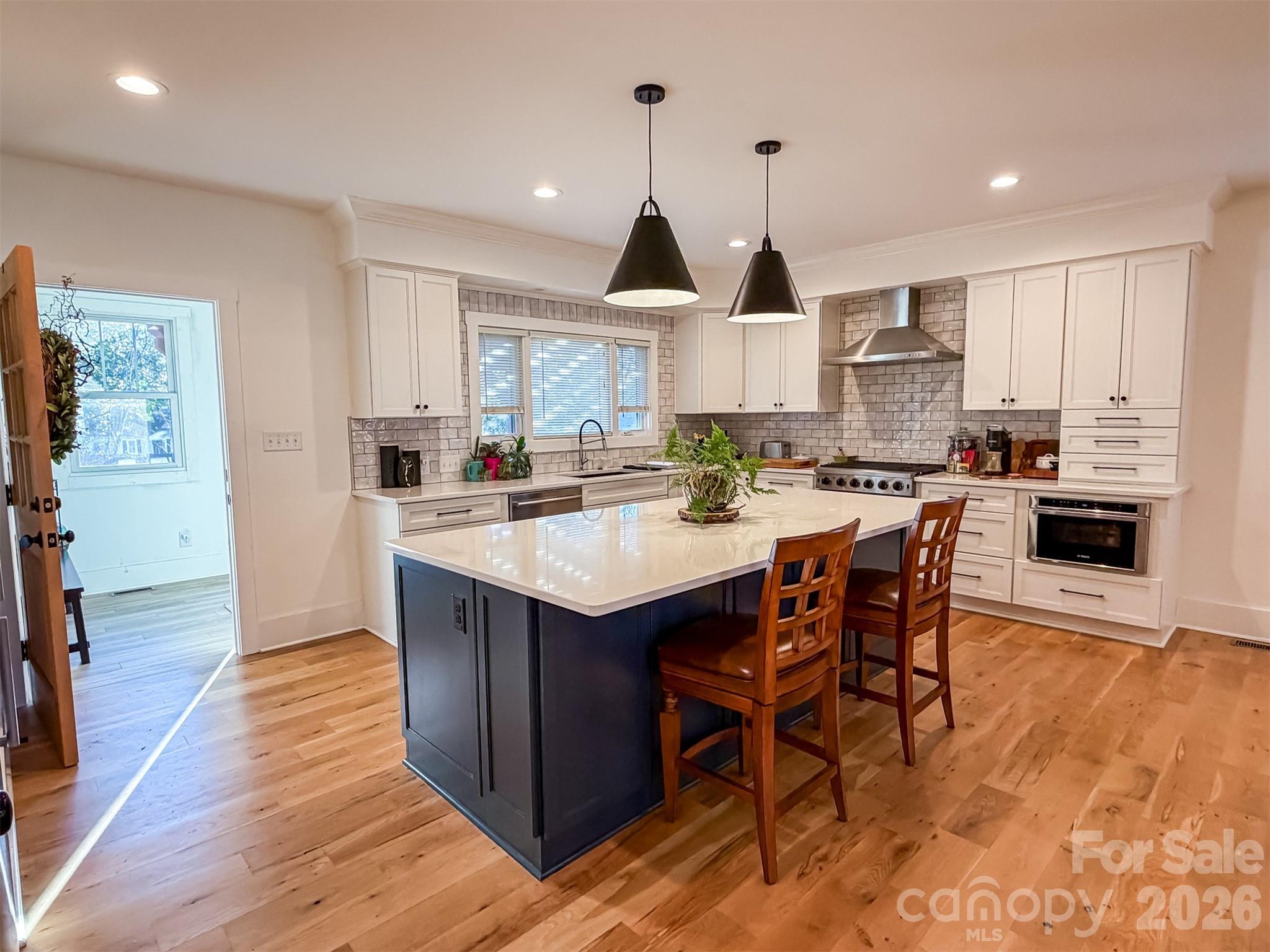 85 20th Avenue Northwest Hickory, NC 28601 - Photo 13 of 47 a kitchen with stainless steel appliances kitchen island granite countertop a table chairs a sink dishwasher a refrigerator and cabinets with wooden floor