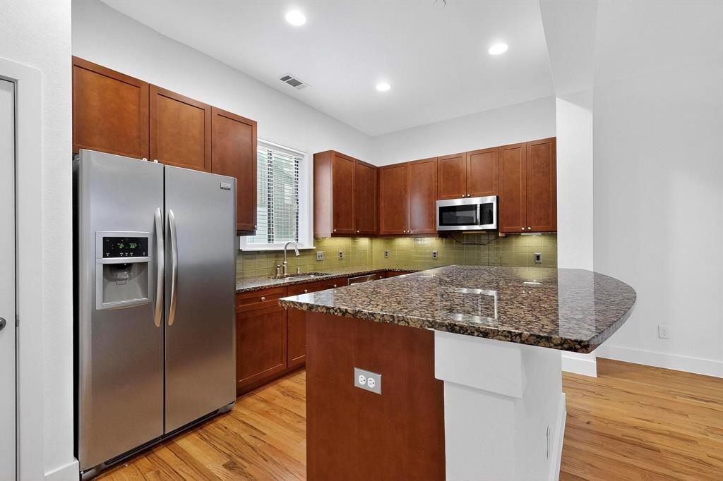 4211 Rawlins Street, Unit 528 Dallas, TX 75219 - Photo 3 of 14 Kitchen featuring wood-finish flooring, stone countertops, stainless steel appliances, recessed lighting, and a tile backsplash