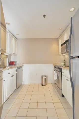 a kitchen with a sink a stove top oven and white cabinets