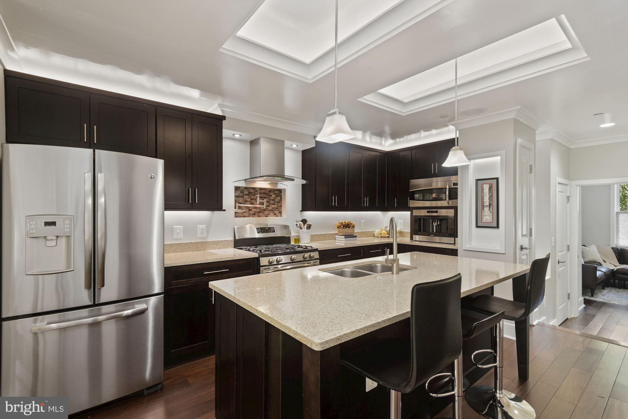 73 U Street Northwest, Unit 1 Washington, DC 20001 - Photo 6 of 30 a kitchen with stainless steel appliances a refrigerator a stove a microwave a dining table and chairs
