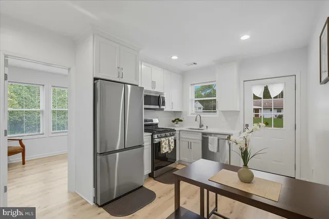 a kitchen with stainless steel appliances a refrigerator a stove a sink a dining table and chairs