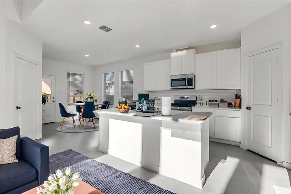 a view of kitchen with stainless steel appliances granite countertop a stove top oven a sink a dining table and chairs