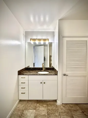 a bathroom with a granite countertop sink and a mirror