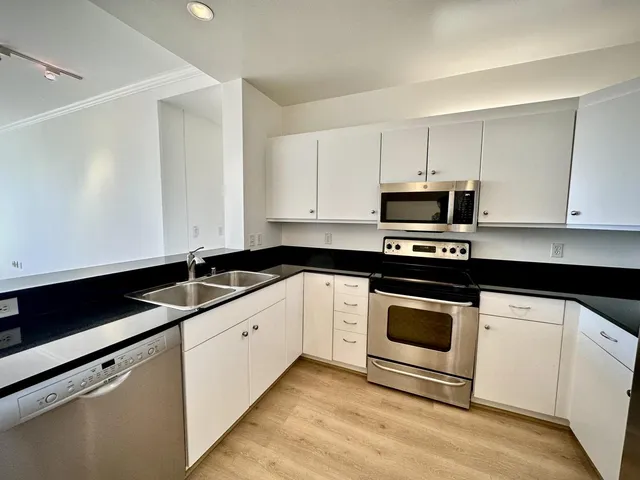 a kitchen with granite countertop white cabinets and appliances