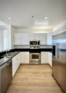 a large kitchen with granite countertop a stove top oven and cabinets