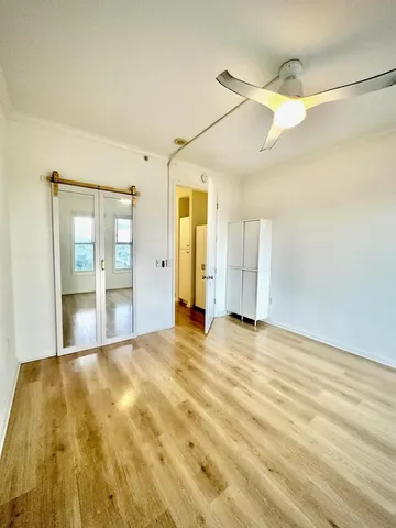 a view of empty room with wooden floor and fan