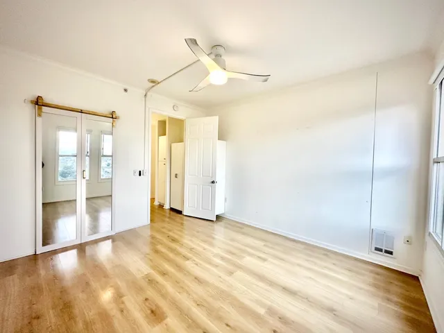 a view of an empty room with cabinet and wooden floor