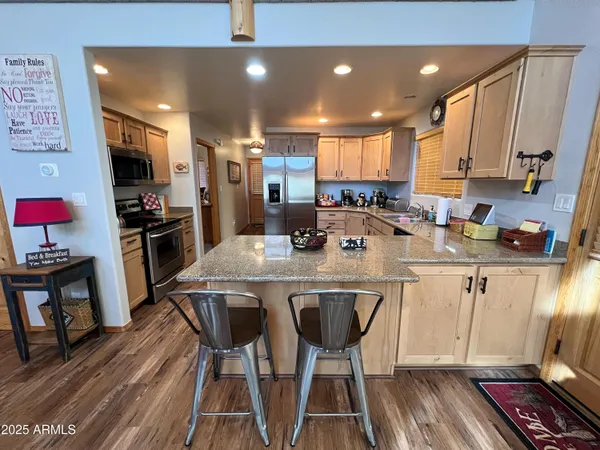 a kitchen with stainless steel appliances a dining table chairs stove refrigerator and cabinets