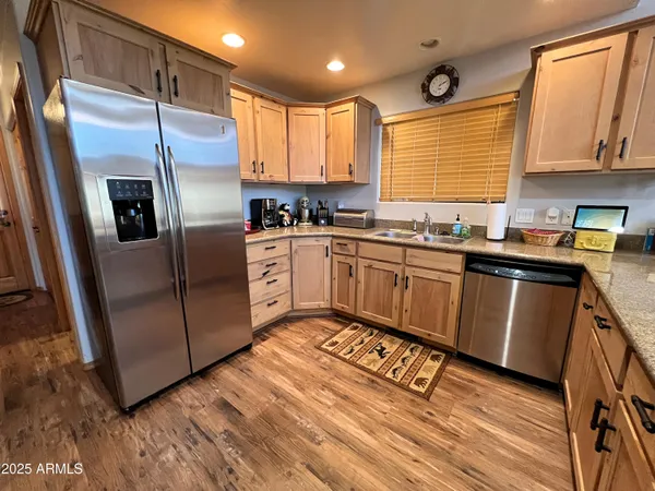 a kitchen with stainless steel appliances granite countertop a sink a stove a refrigerator with wooden floors and cabinets