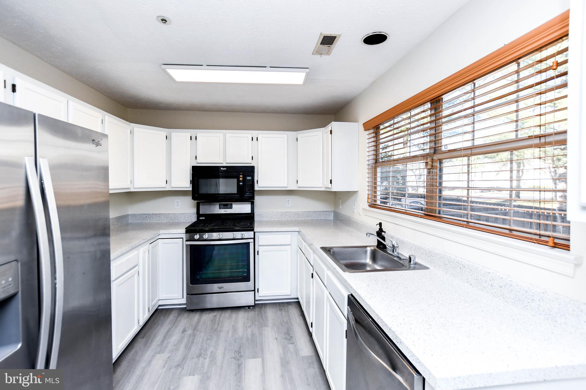 5908 Grenfell Loop Bowie, MD 20720 - Photo 15 of 65 a kitchen with stainless steel appliances a stove a sink a refrigerator and a window