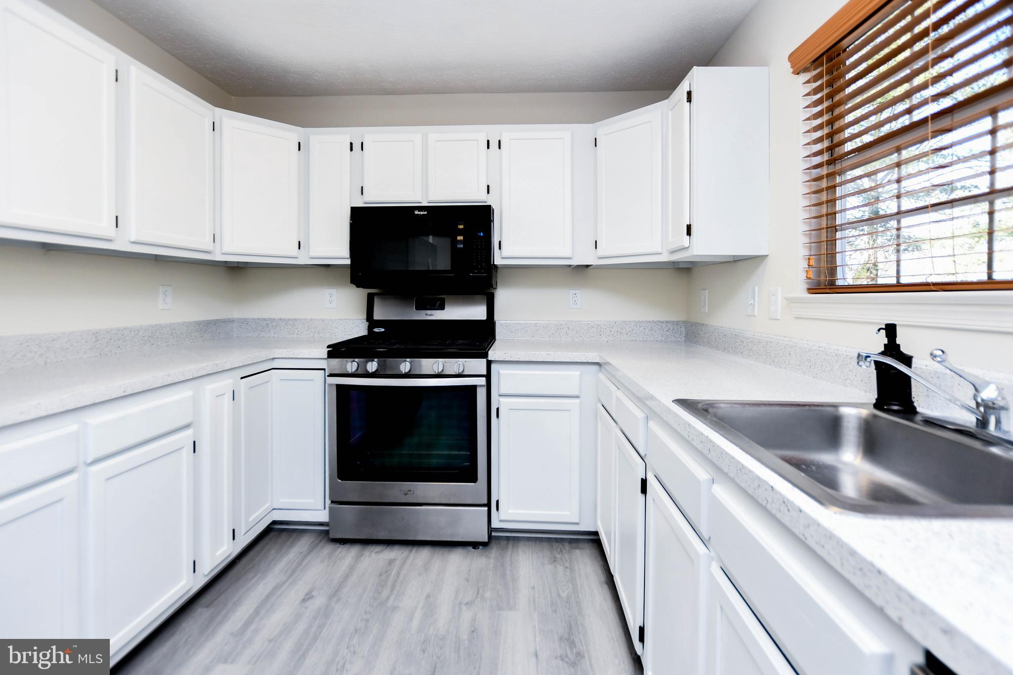 5908 Grenfell Loop Bowie, MD 20720 - Photo 17 of 65 a kitchen with cabinets appliances a sink and a window