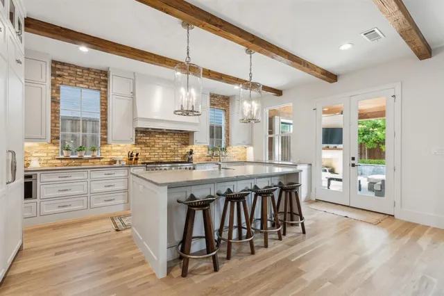 a kitchen with stainless steel appliances granite countertop a stove a sink dishwasher and a dining table with wooden floor