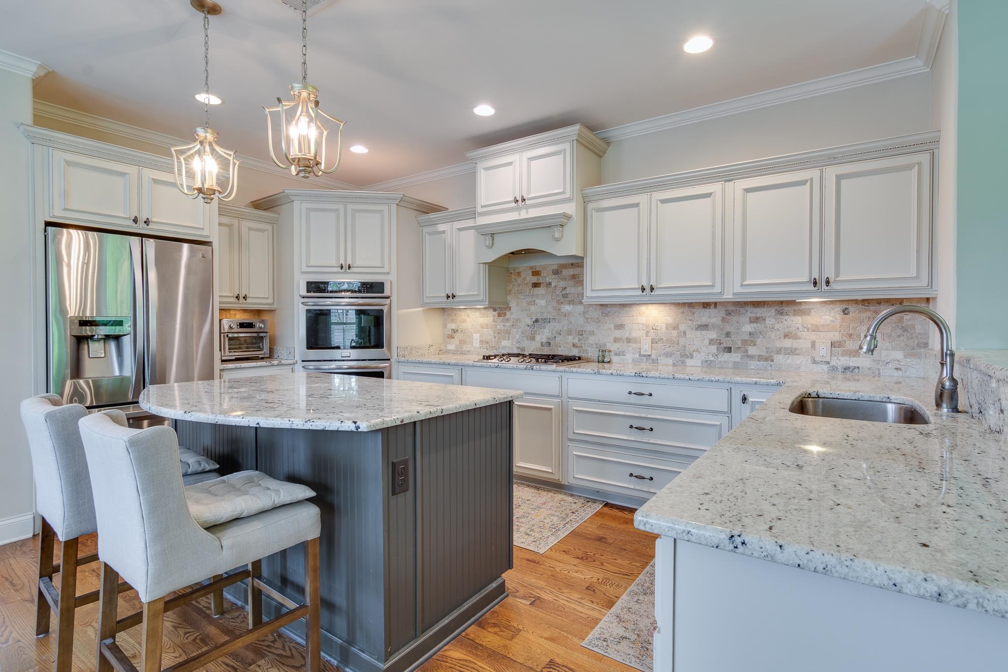 901 Colbert Street South Collierville, TN 38017 - Photo 19 of 37 Kitchen featuring light stone countertops, ornamental molding, decorative light fixtures, white cabinetry, and backsplash