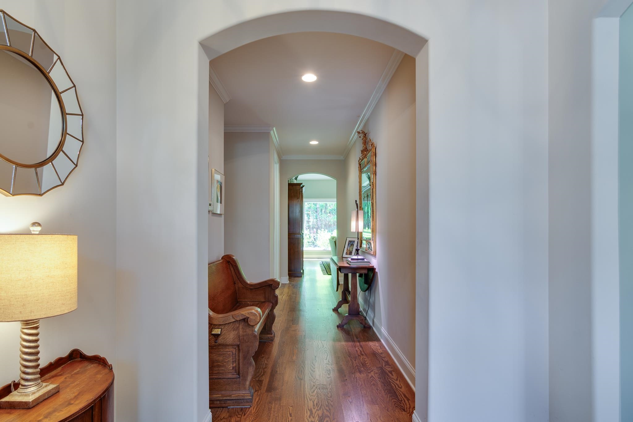 Corridor with arched walkways, dark wood-style flooring, ornamental molding, and recessed lighting