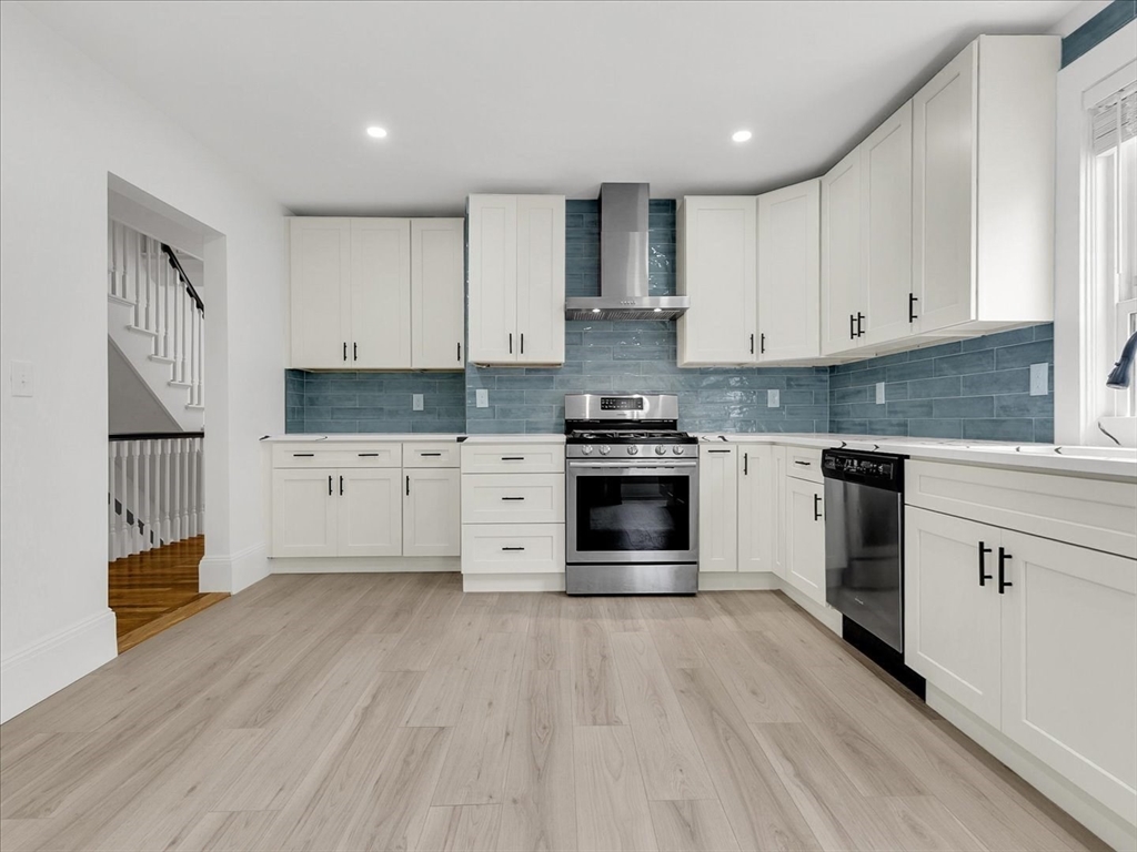 186 Main Street, Unit 2 Wayland, MA 01778 - Photo 23 of 41 a kitchen with stainless steel appliances granite countertop a stove top oven a sink dishwasher and white cabinets with wooden floor