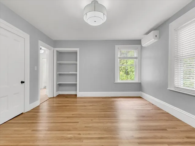 an empty room with wooden floor closet and windows
