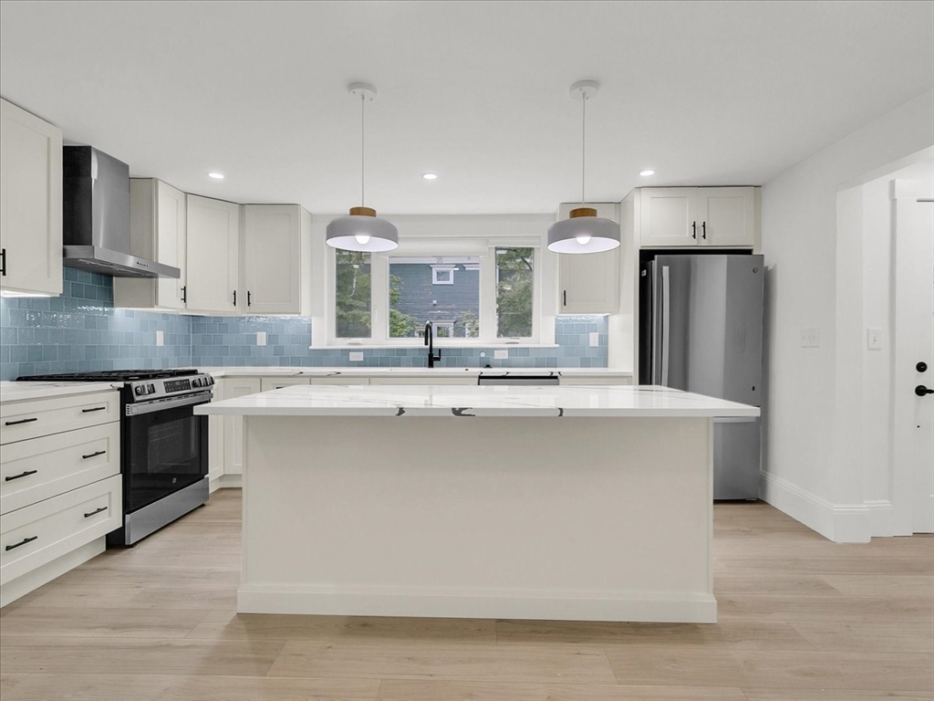 186 Main Street, Unit 2 Wayland, MA 01778 - Photo 4 of 41 a large kitchen with stainless steel appliances a large counter top a stove a refrigerator and a sink