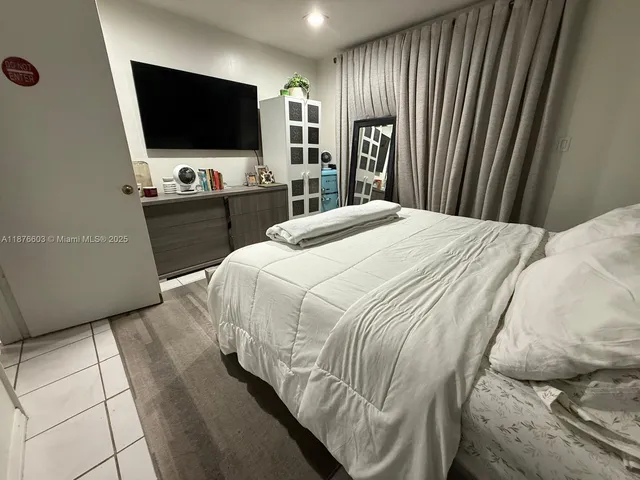 a bedroom with a bed a television and a large window