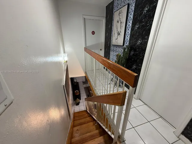 a view of staircase with railing and white walls