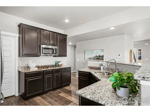 a kitchen with stainless steel appliances kitchen island granite countertop a sink a stove a microwave a dining table and chairs