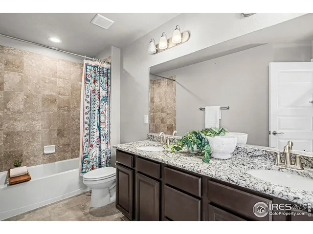 a bathroom with a granite countertop sink mirror vanity bathtub and toilet
