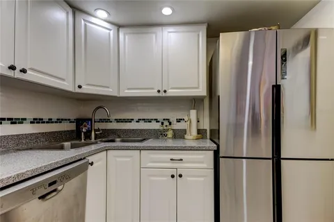 a kitchen with stainless steel appliances granite countertop a refrigerator a stove a sink and white cabinets