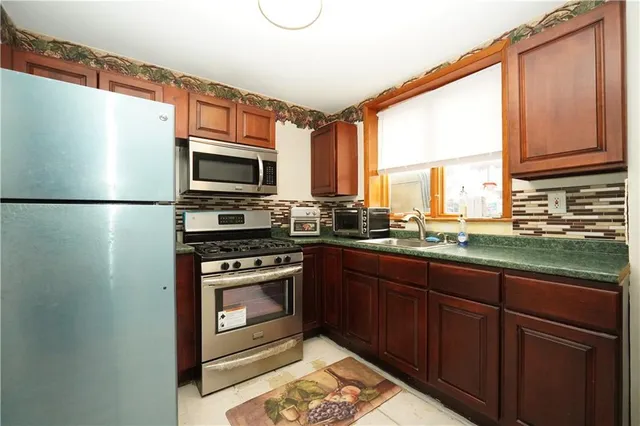 a kitchen with stainless steel appliances granite countertop a refrigerator a stove a sink and a microwave