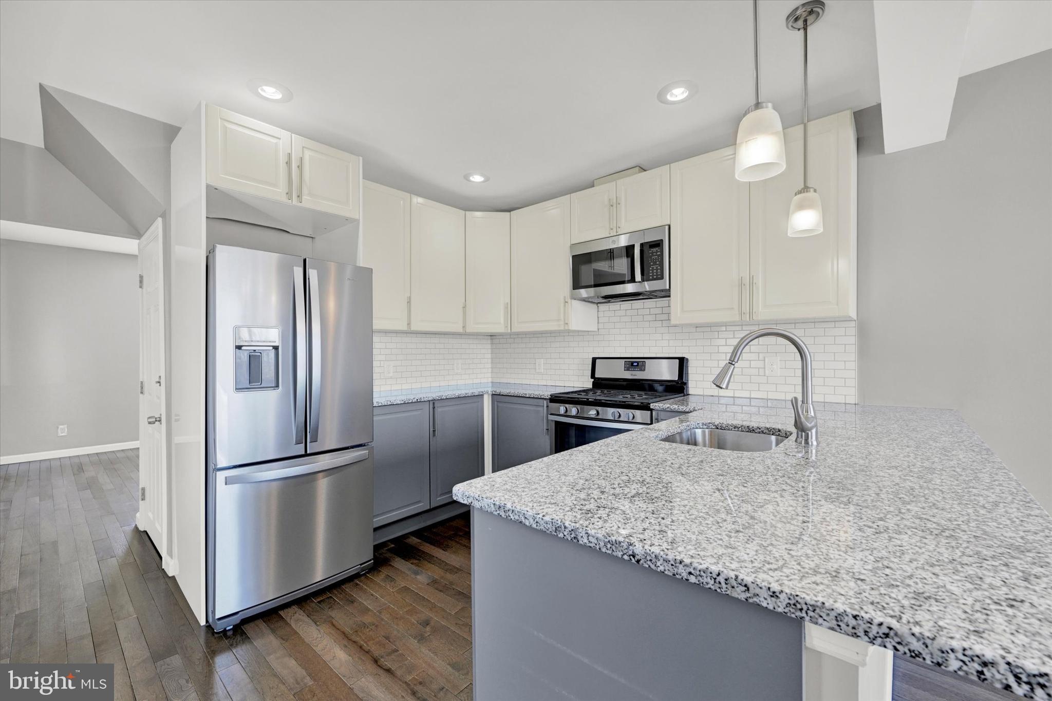 a kitchen with granite countertop a refrigerator and a sink