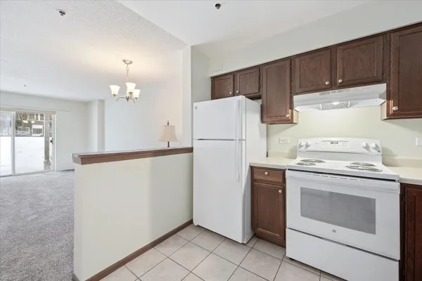 a white refrigerator freezer and a stove sitting inside of a kitchen with granite countertop white cabinets
