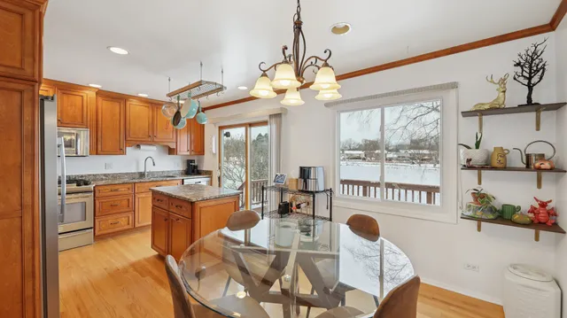 a open kitchen with stainless steel appliances granite countertop a stove a sink a refrigerator dining table and chairs with wooden floor