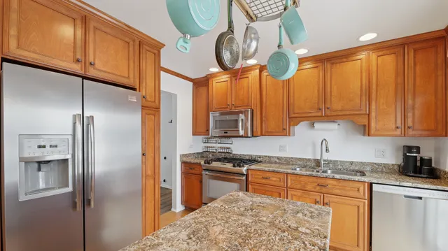 a kitchen with stainless steel appliances granite countertop a refrigerator a stove and a sink with granite countertops