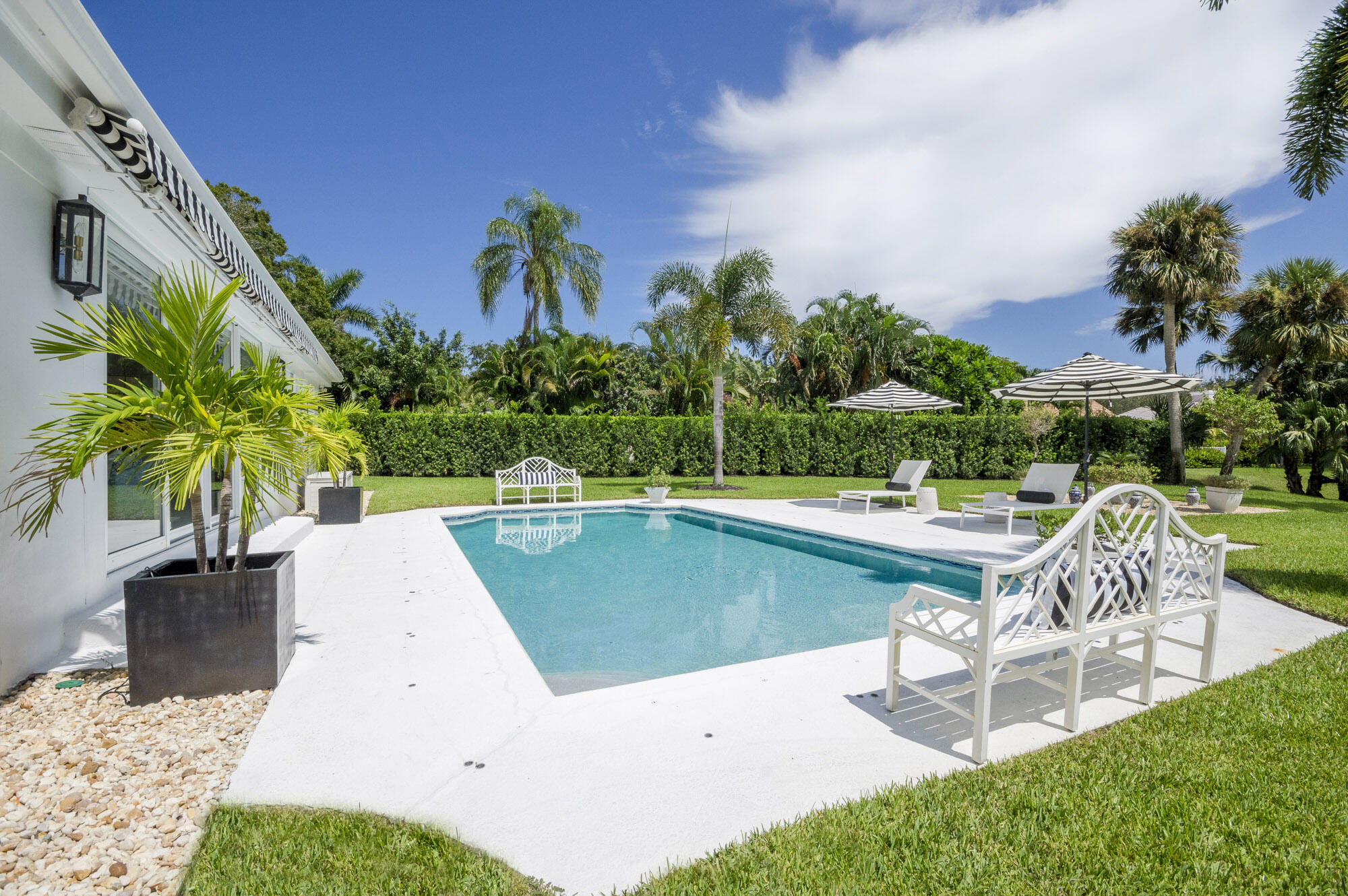 10182 Southeast Acorn Way Jupiter, FL 33469 - Photo 26 of 38 a view of a swimming pool with lawn chairs plants and palm trees