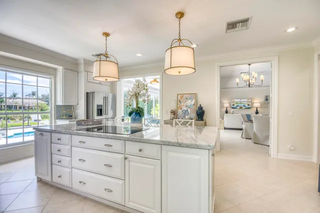 a kitchen with kitchen island granite countertop white cabinets and chandelier