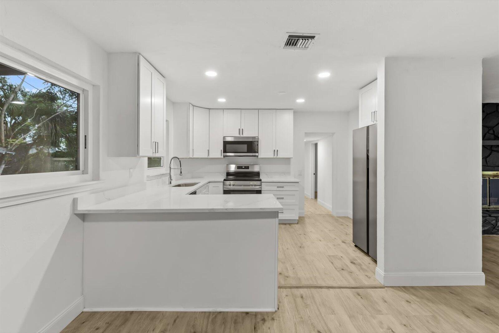 603 Southwest 14th Street Okeechobee, FL 34974 - Photo 12 of 41 a kitchen with kitchen island white cabinets and refrigerator